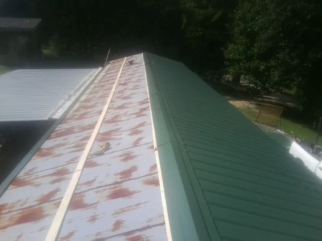 Old rusted panels beside newly installed green metal roofing — Wind Damage Roof Repair by Roofing Brothers in Irwin